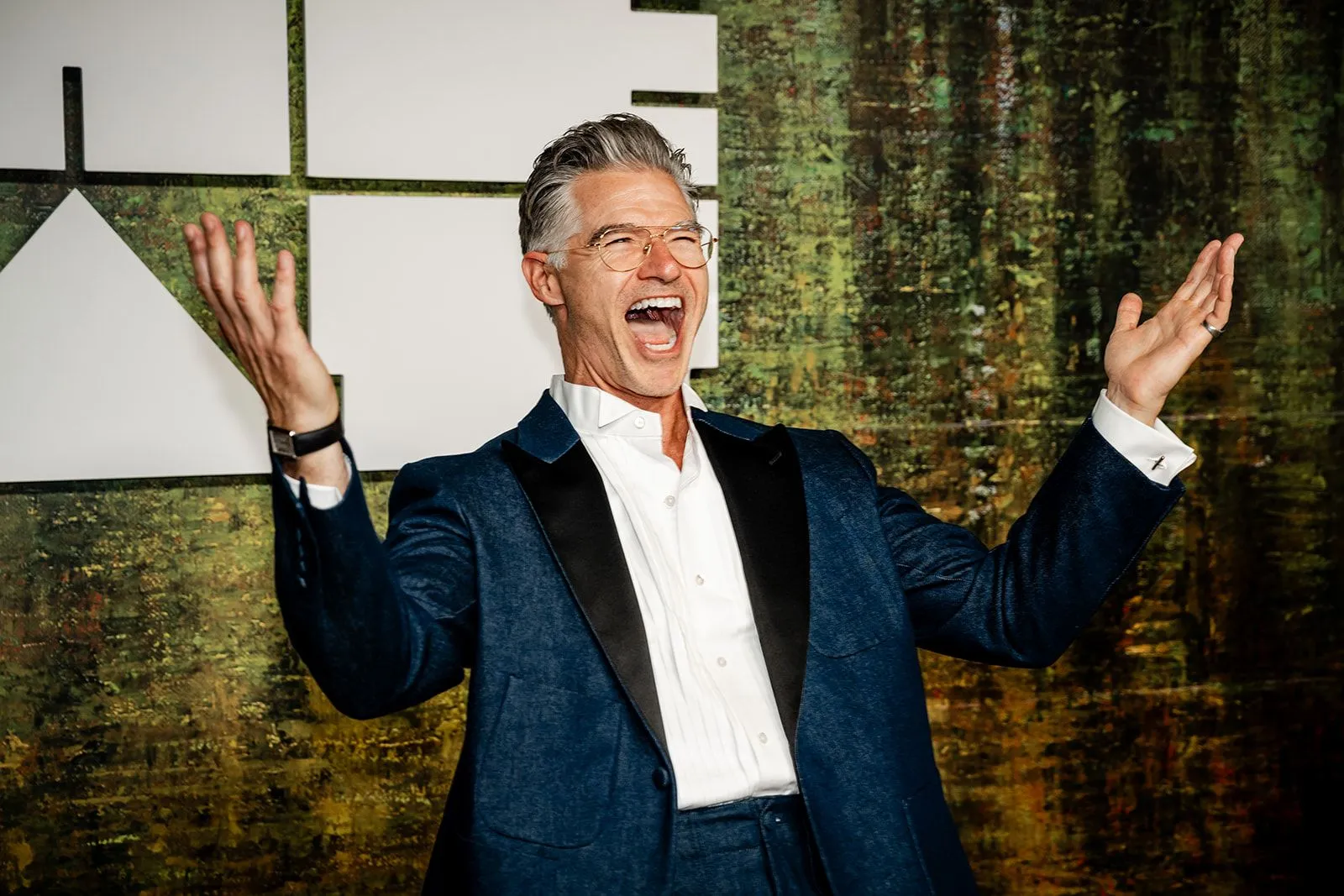 A guest celebrating with arms raised at the step and repeat.