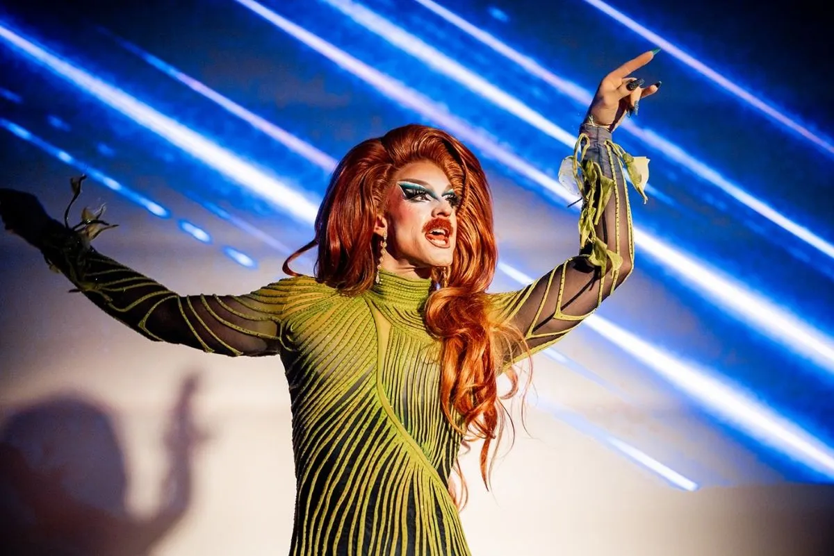 Pattie Gonia performing in front of streaks of blue light.